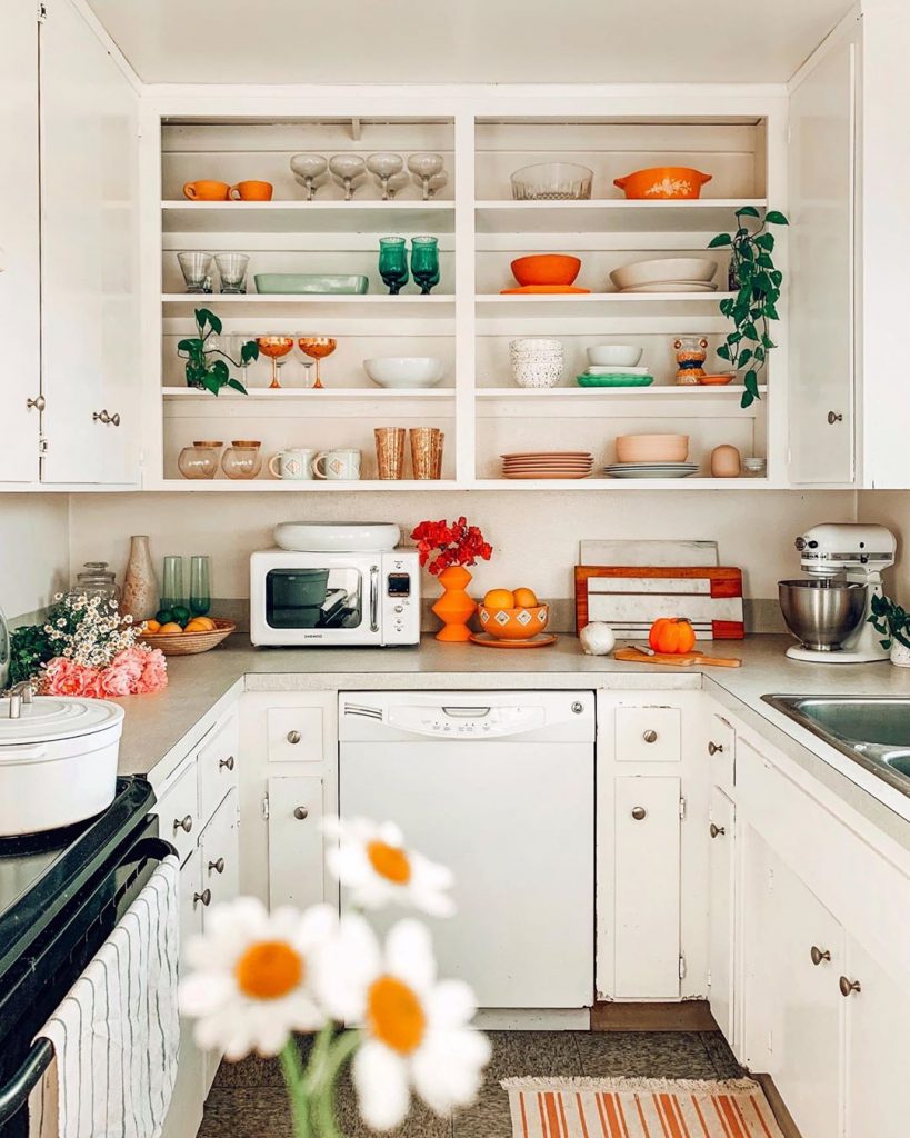 instagram de decoração - cozinha branca com itens laranja e branco na prateleira e armários superiores, eletrodomésticos e decoração laranja e branco