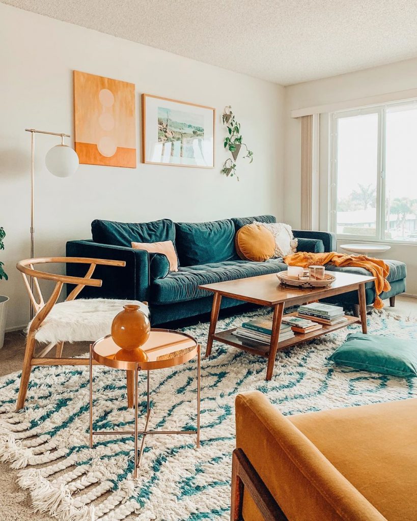 instagram de decoração - sofá azul na sala, com quadros e planta, cadeiras e tapete, mesa de centro de madeira