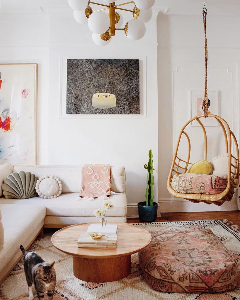 instagram de decoração - cadeira pendurada, sofá na sala branco, tapete colorido, mesa de centro de madeira, parede branca com quadro