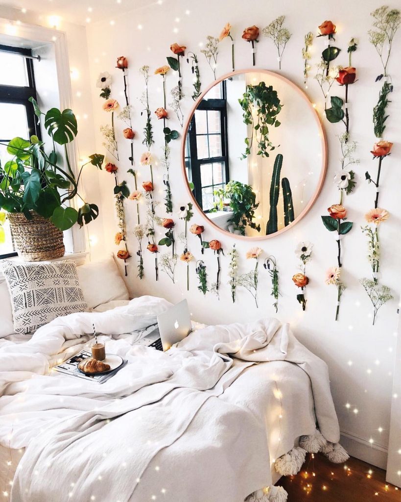 instagram de decoração espelho na parede, quarto, cama com cobertas e flores penduradas ao redor do espelho na parede